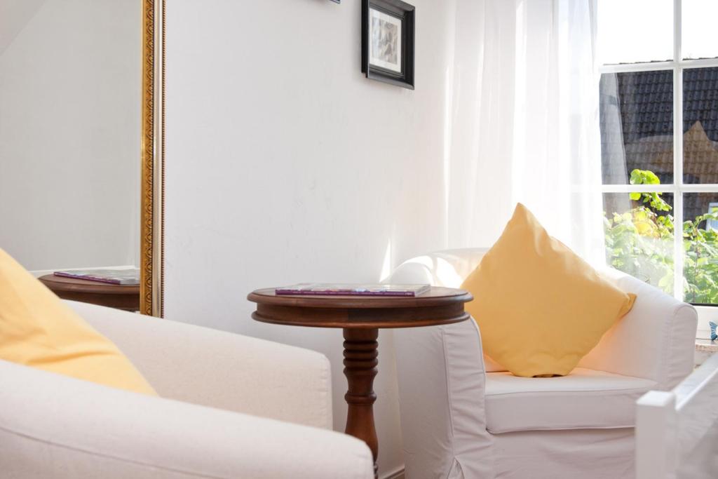 a living room with two white couches and a table at Landhaus Lillesand in Esens