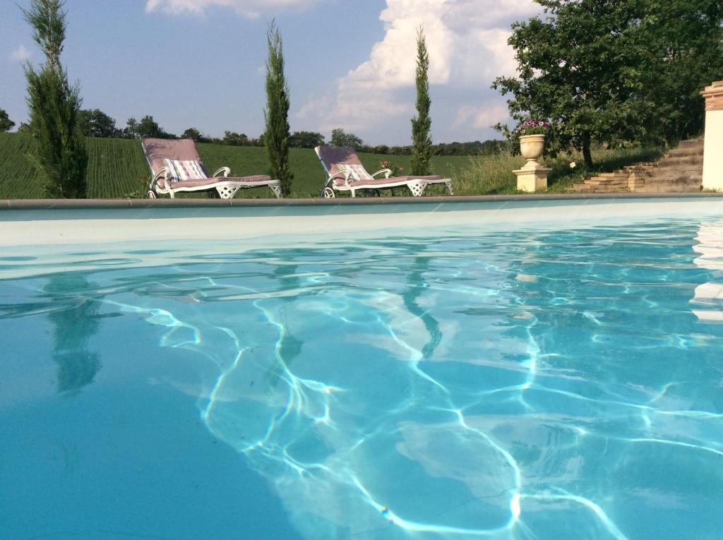 a swimming pool with two chairs in a yard at Maison En Cramaillan in Bragayrac