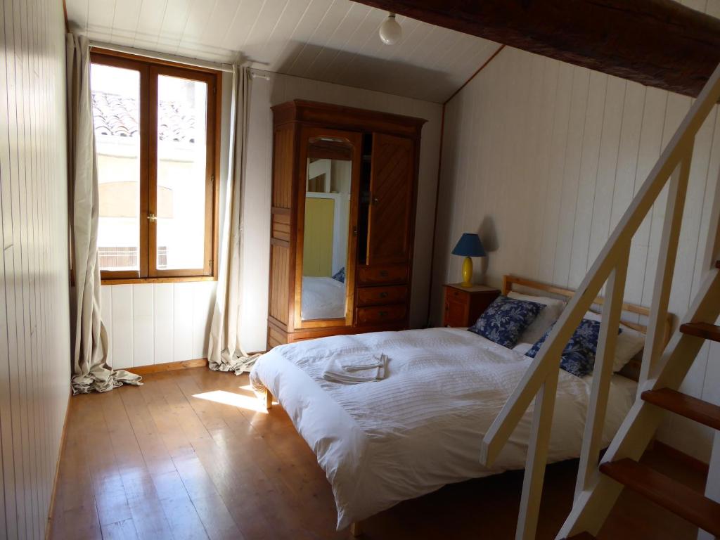 um quarto com uma cama e uma grande janela em Well equipped village house close to historic centre - Pézenas em Pézenas