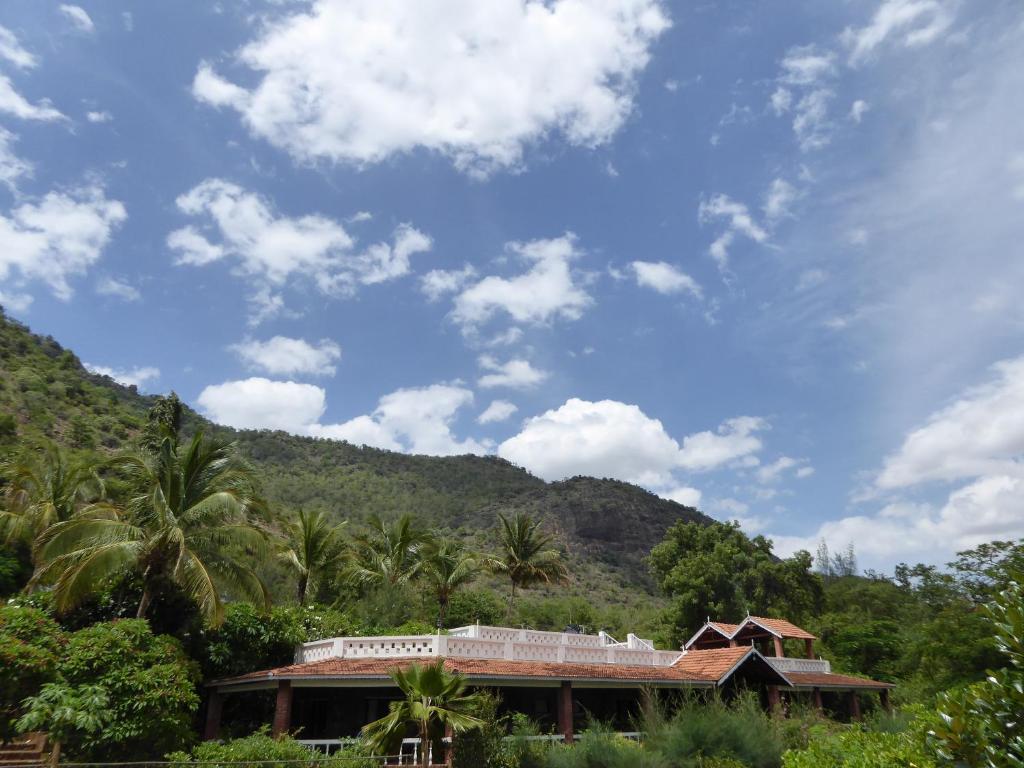 a building with palm trees in front of a mountain at Cardamom House in Sembatti