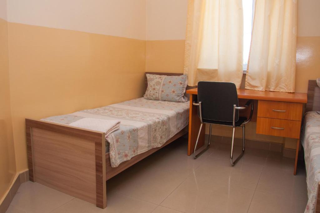 a bedroom with a bed and a desk and a chair at Sakura Guesthouse in Bishkek