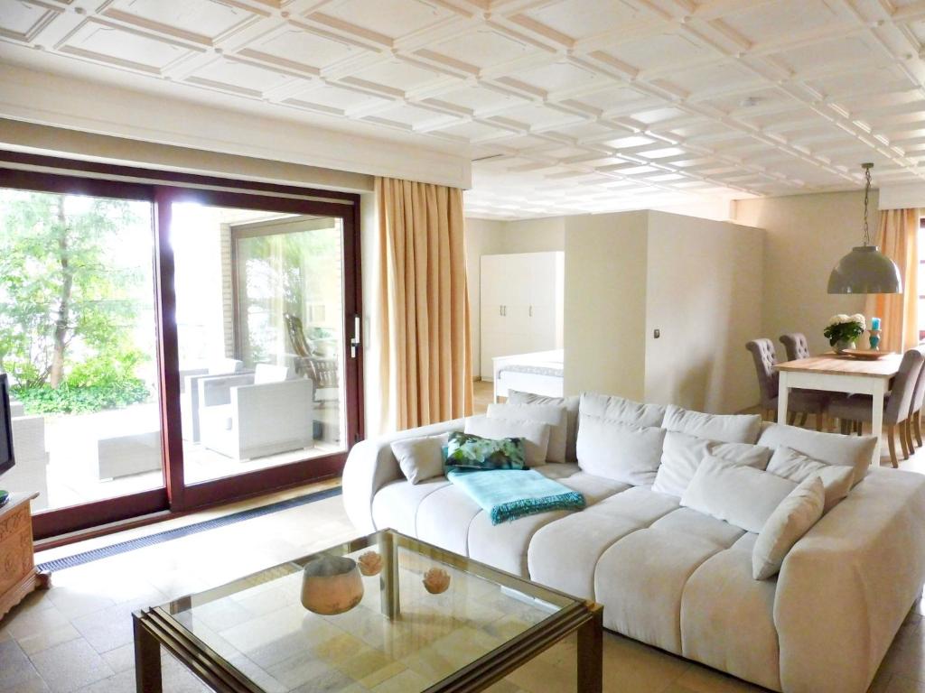 a living room with a white couch and a glass table at Haus Kranenborgh im Mühlenspiegel Steinhude am Meer in Steinhude