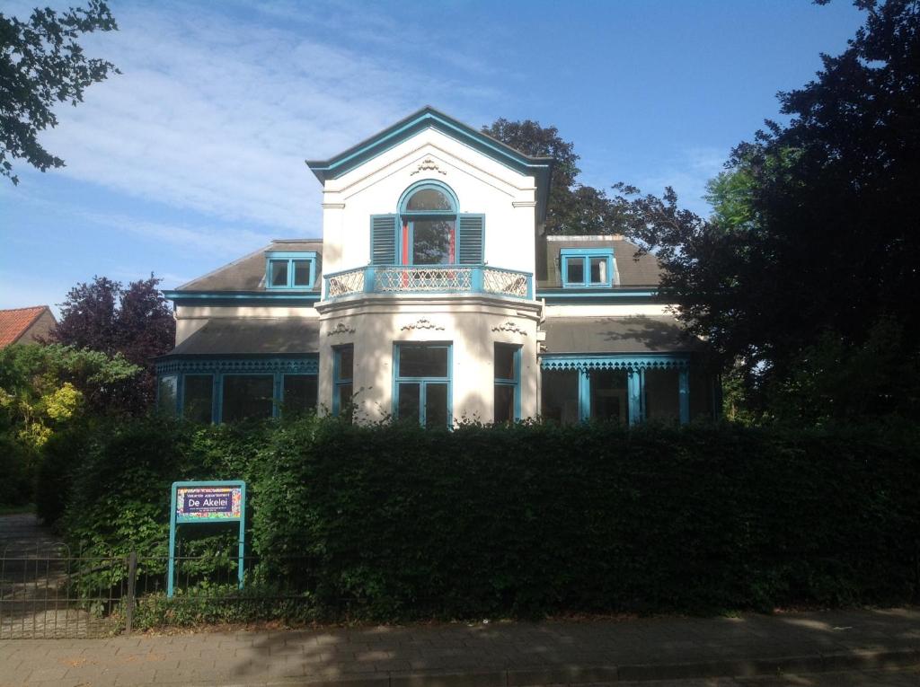 een groot wit huis met een bord ervoor bij De Akelei in Lochem