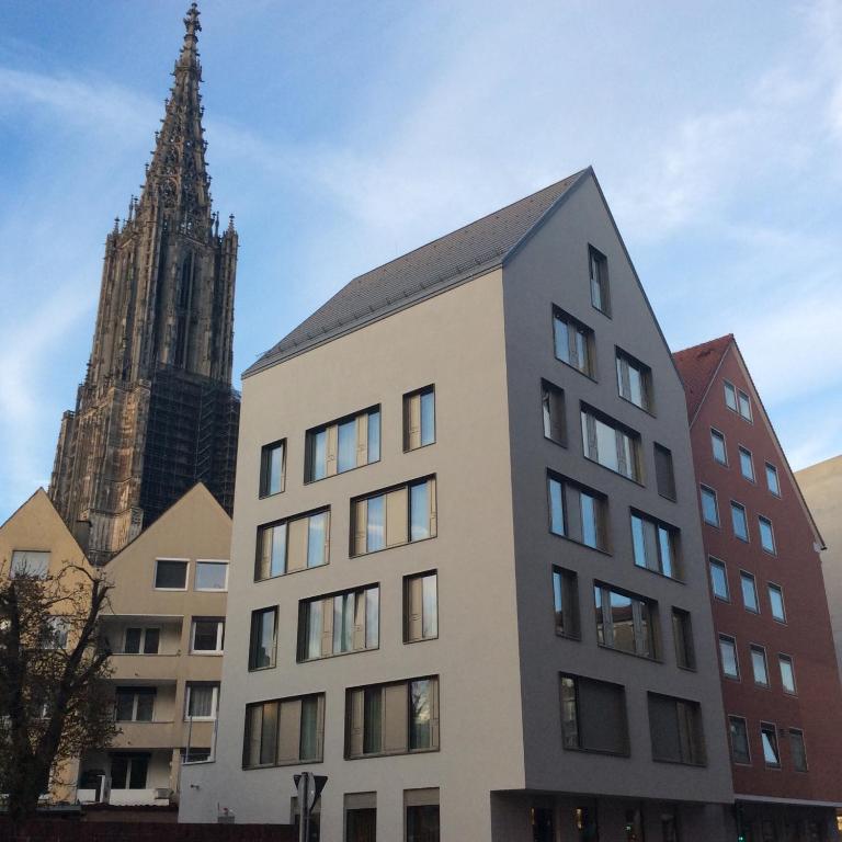 a tall building with a church in the background at Hotel Goldenes Rad in Ulm