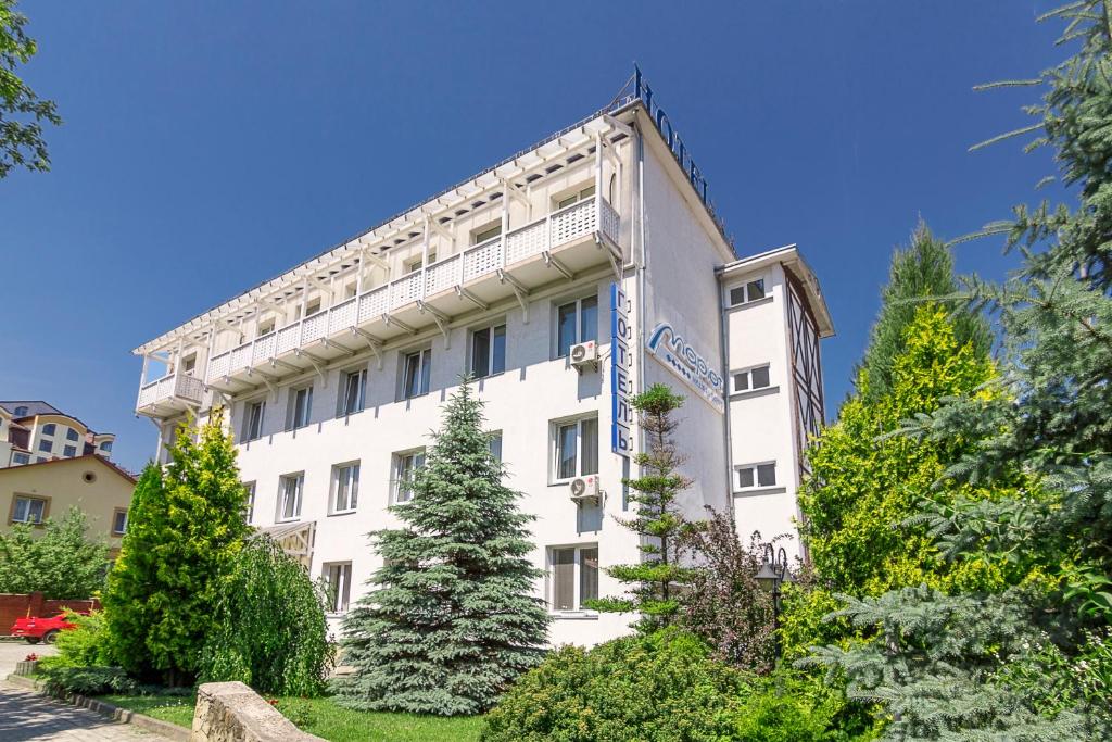 a white building with trees in front of it at Mariot Medical Center Hotel in Truskavets