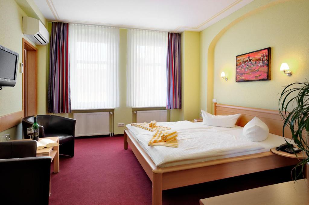 a hotel room with a bed and a chair at Hotel-Pension Am Schwanenteich in Lutherstadt Wittenberg