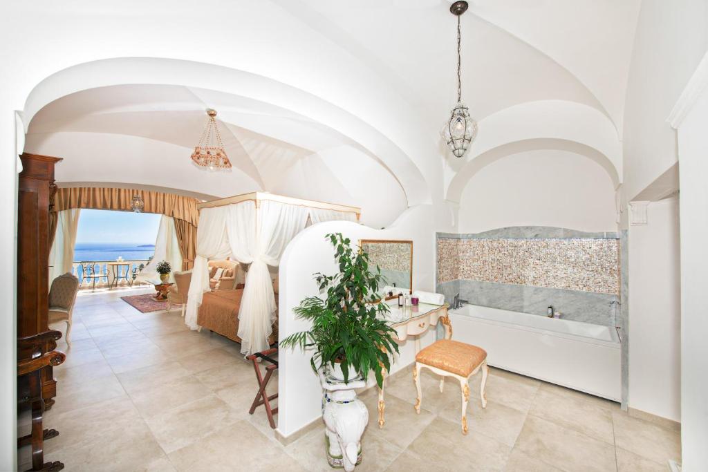a bedroom with a bed and a tub and a table at Hotel Villa Gabrisa in Positano