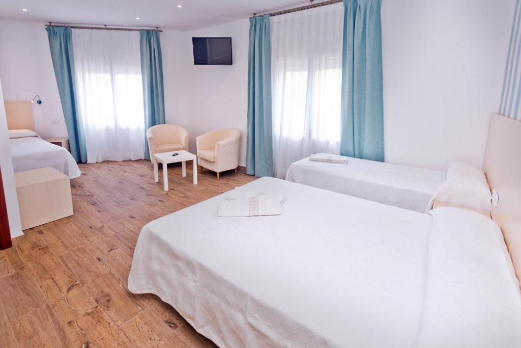 a hotel room with two beds and two chairs at Mercè in Pineda de Mar