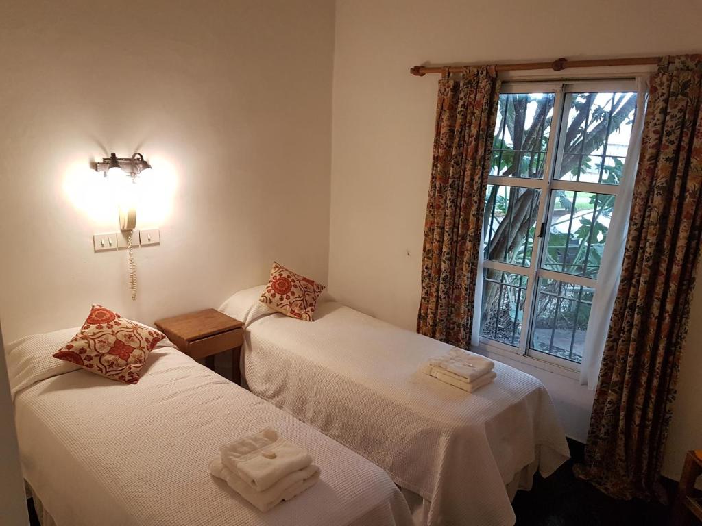 2 camas individuales en una habitación con ventana en Hosteria El Colonial en Baradero