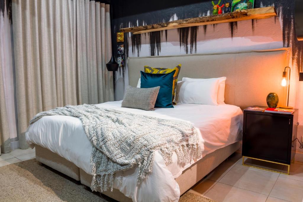 een slaapkamer met een groot wit bed met kussens bij Bly B&B in Pretoria