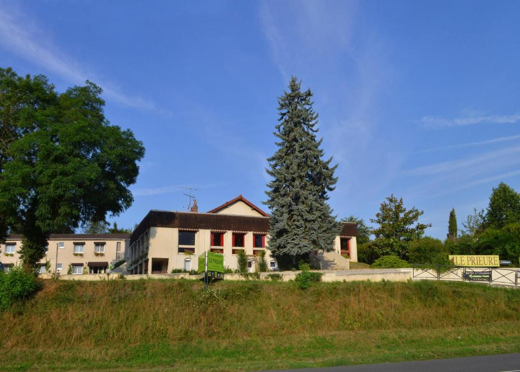 un edificio con un gran árbol delante de él en Logis Hotel Le Prieure en Saint-Marcel