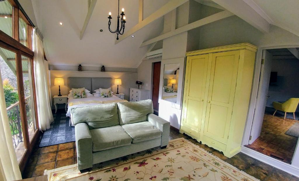 een slaapkamer met een bed, een bank en een stoel bij Aan De Vliet Guest House in Stellenbosch