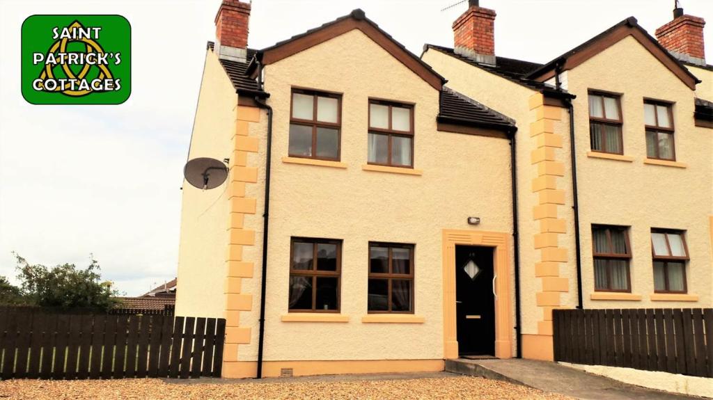 a white brick house with a black fence at Saint Patrick's Cottages (Downpatrick) in Downpatrick