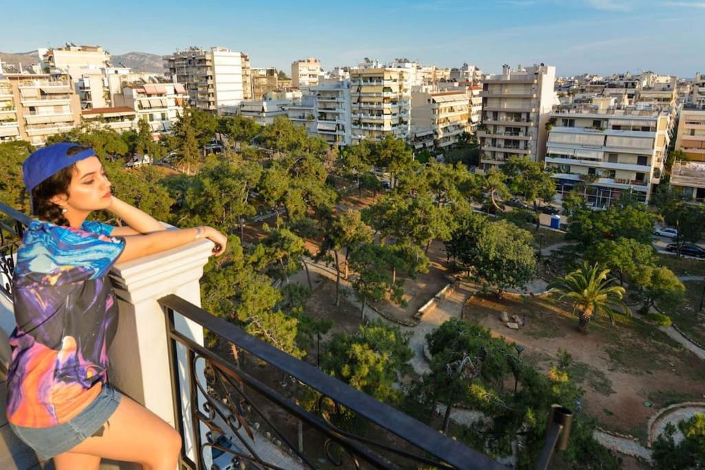 une femme debout sur un balcon donnant sur une ville dans l'établissement 165 sm Penthouse Maisonette Apartment, à Athènes