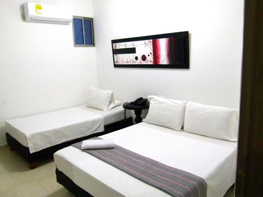 een kamer met 2 bedden en een tv aan de muur bij Hotel Central in Sincelejo