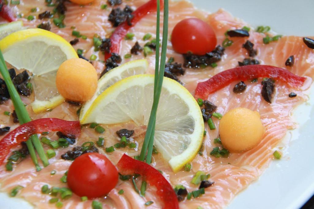a plate of fish with tomatoes and lemon slices at Hôtel De France in Chalabre