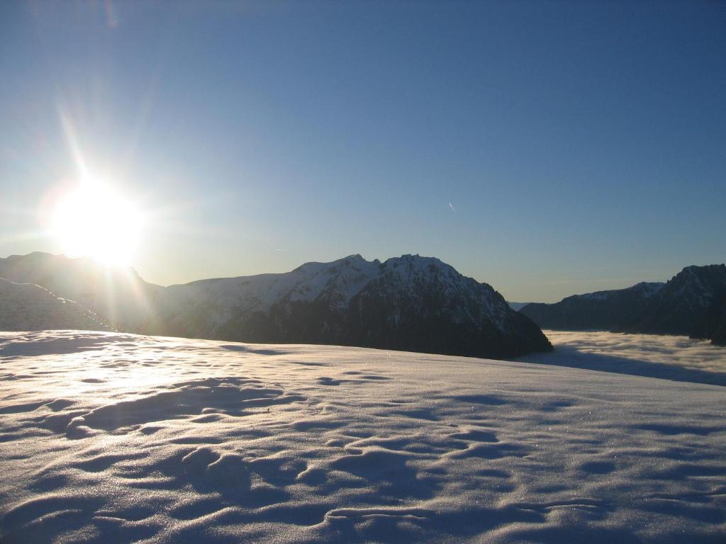 a snow covered mountain with the sun in the background at Hôtel Le Dôme in L&#39;Alpe-d&#39;Huez