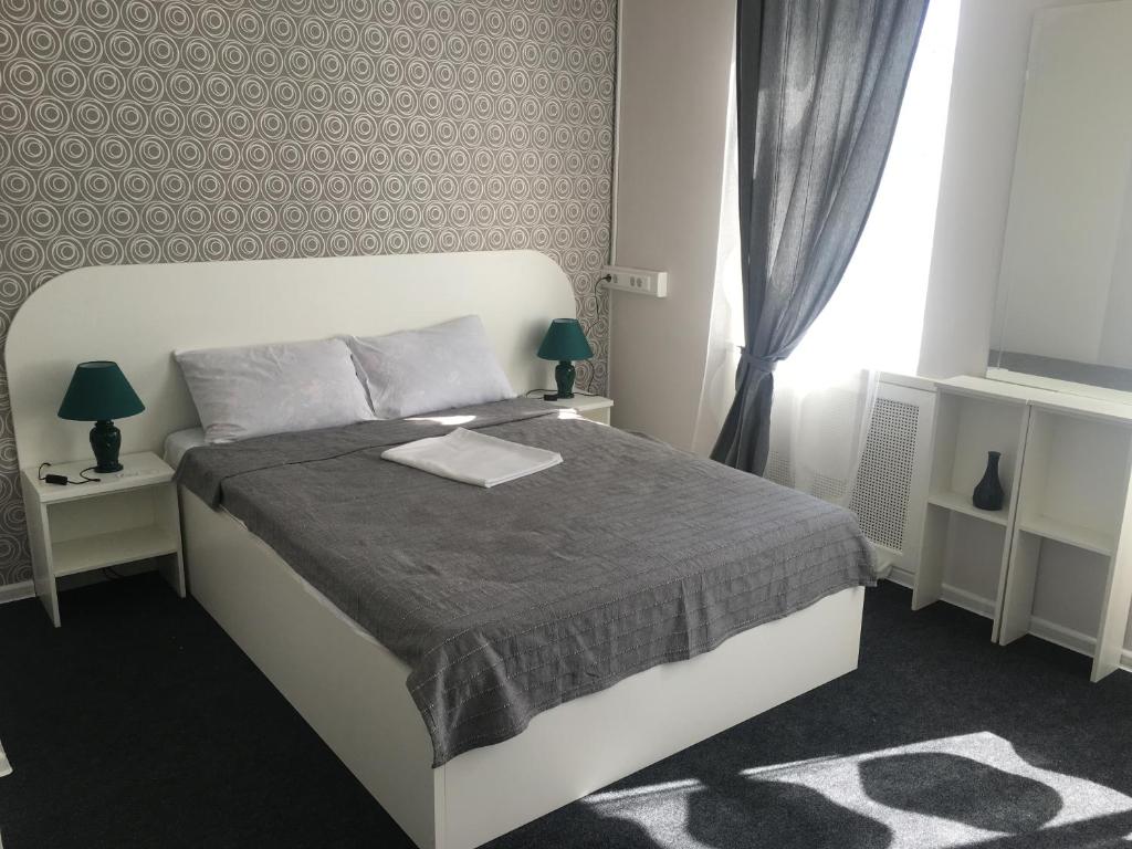 モスクワにあるミニホテル リンゼーのベッドルーム1室(白いベッド1台、テーブル2台、窓付)