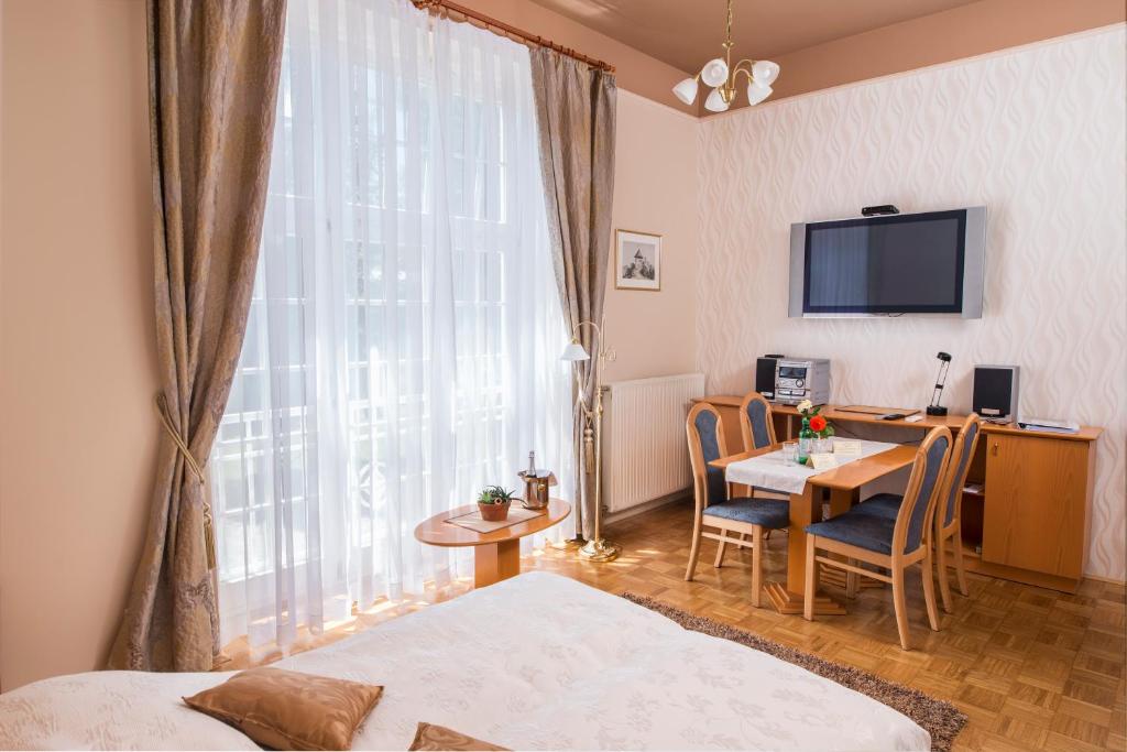 a hotel room with a desk and a table with chairs at Apartment Vila Golf in Rogaška Slatina
