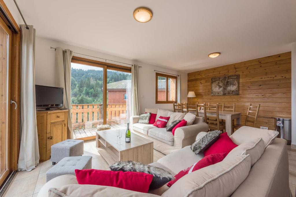 a living room with two white couches and a table at L'Eden Ski aux Pieds in Morillon