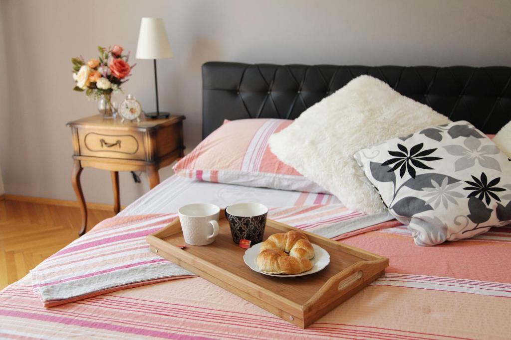 uma bandeja com duas chávenas e um prato de croissants numa cama em London Apartment em Belgrado