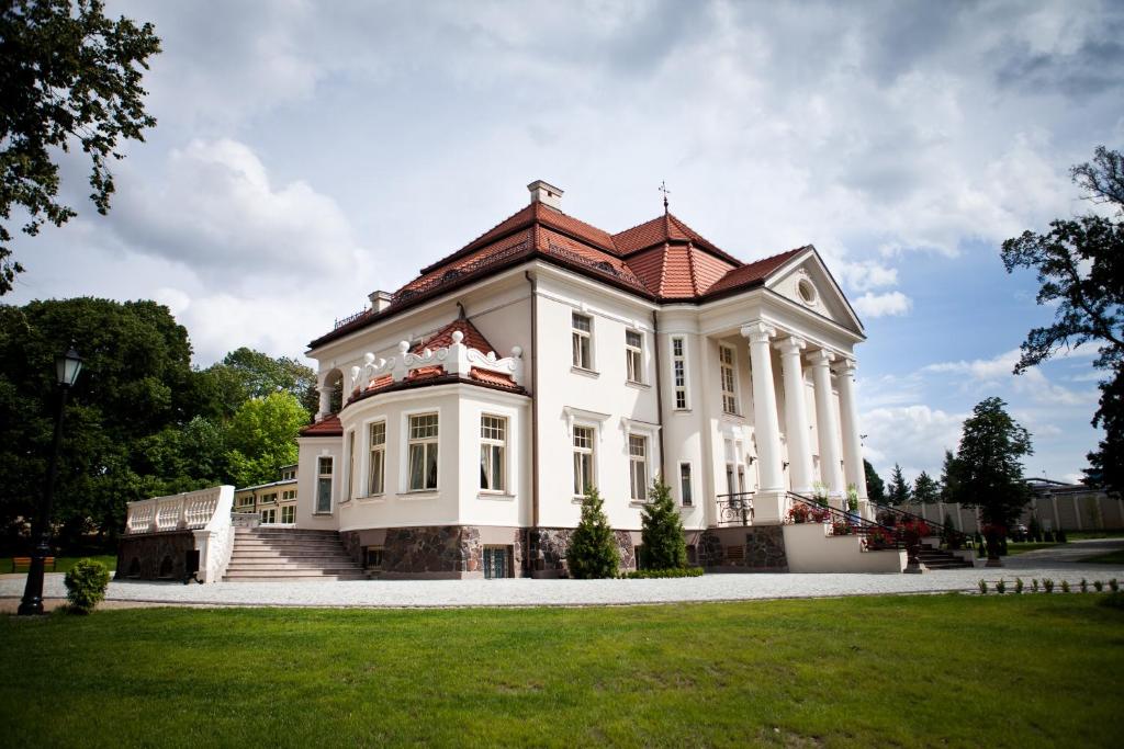 una gran casa blanca con techo rojo en Pałac Tłokinia en Kalisz