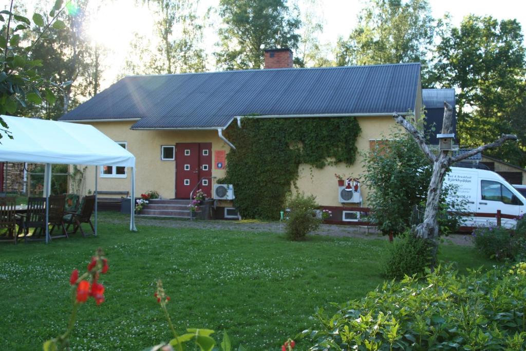 uma casa com um telhado preto e um quintal em Bed & Breakfast Björkhyddan em Rumma