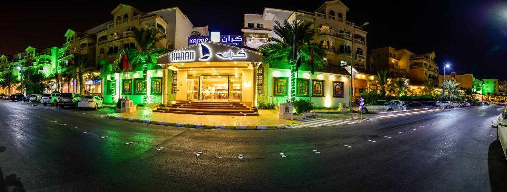 فندق كران في الجبيل: مبنى ذو اضاءة خضراء على شارع المدينة ليلا