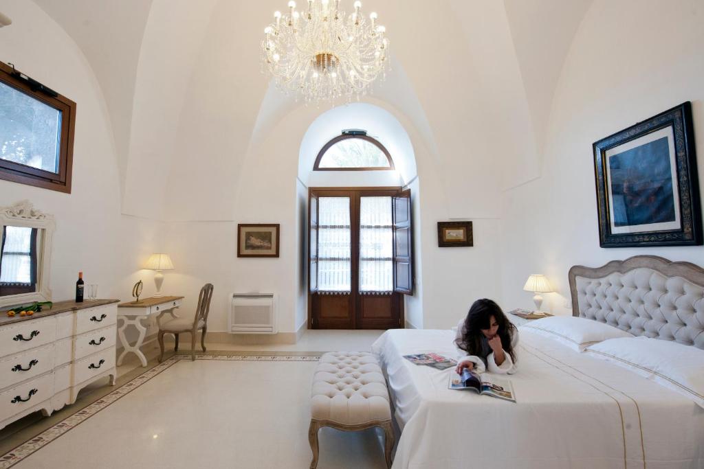 Una ragazza sdraiata su un letto in una camera da letto di Resort Acropoli a Pantelleria