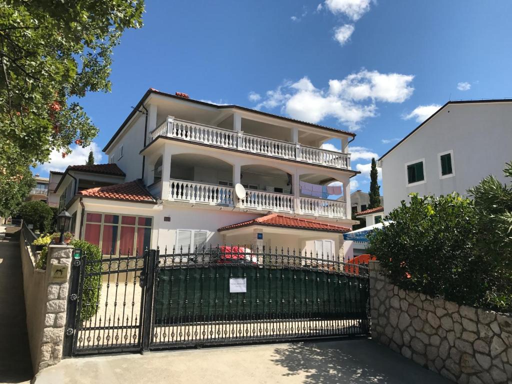 uma grande casa branca com uma cerca preta em Apartment Novi Vinodolski em Novi Vinodolski
