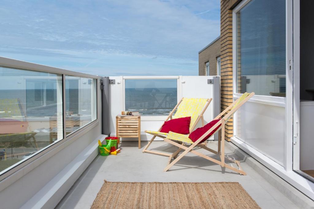 a rocking chair on a balcony with a view of the ocean at Kite View in Noordwijk aan Zee