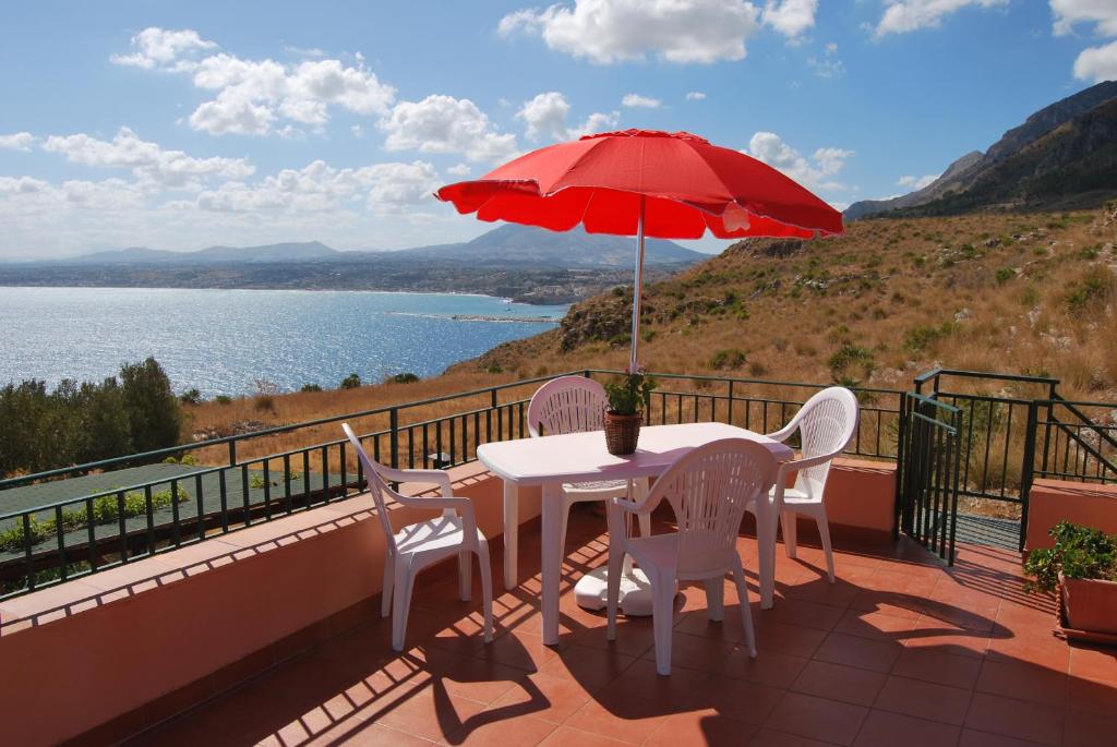 カステッランマーレ・デル・ゴルフォにあるCasa Vacanze La Terrazza Sul Golfoの赤い傘付きのバルコニーにテーブルと椅子