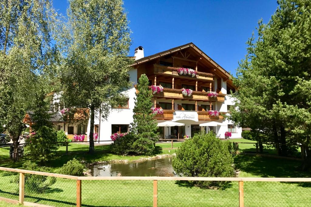 een groot huis met een vijver ervoor bij Hotel Arnaria in Ortisei