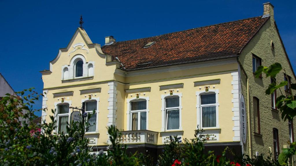 una gran casa amarilla con techo marrón en Hotel Haus Wagner, en Frechen