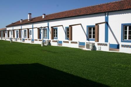 a large white building with a green field in front of it at Monte das Faias Cork Farm Hotel in Grândola