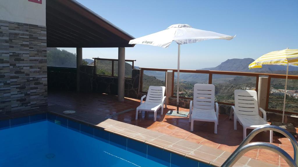 einen Pool mit Stühlen und einem Sonnenschirm in der Unterkunft Casa Rural de Perera in San Bartolomé de Tirajana