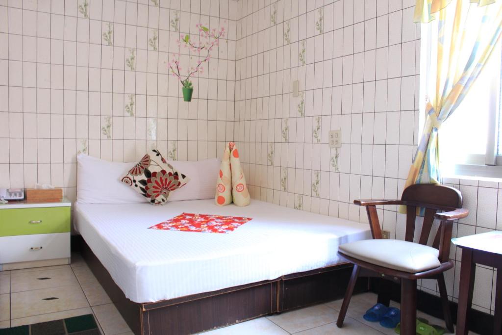 a small bedroom with a white bed and a chair at Hsin Hsin Hotel in Miaoli