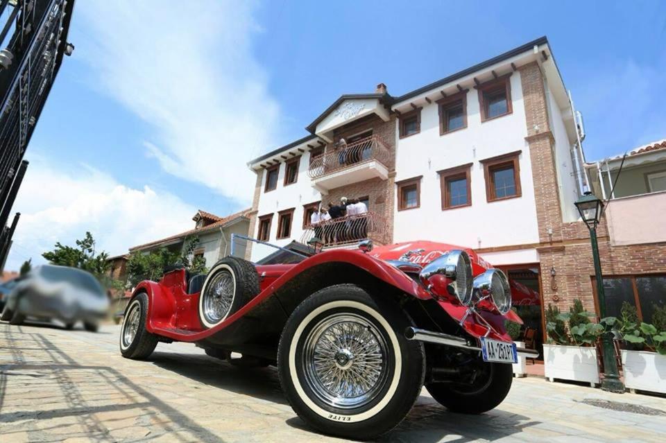 czerwony samochód zaparkowany po stronie ulicy w obiekcie Hotel Bujtina Ollga w mieście Pogradec