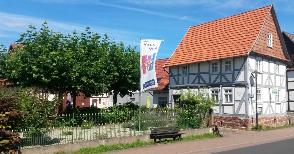 une maison blanche avec un toit rouge et un banc dans l'établissement Villa Velo, à Eschwege