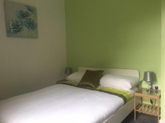 um pequeno quarto com uma cama com lençóis brancos em Townhouse @Richmond Street Stoke em Stoke-on-Trent