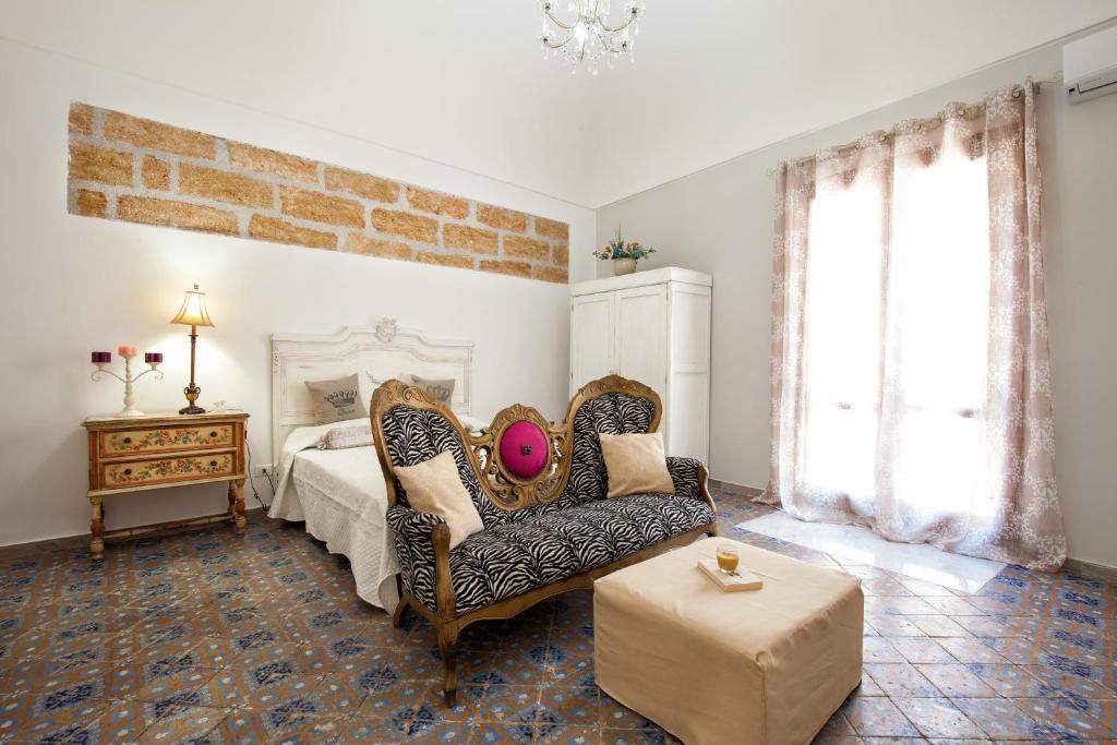 a bedroom with a bed and a couch and a chair at Le Alcove in Cinisi