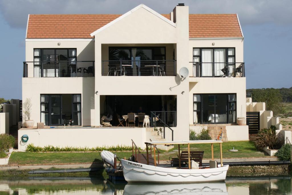 a house on the water with a boat in front at Le Marina B&B in Velddrif