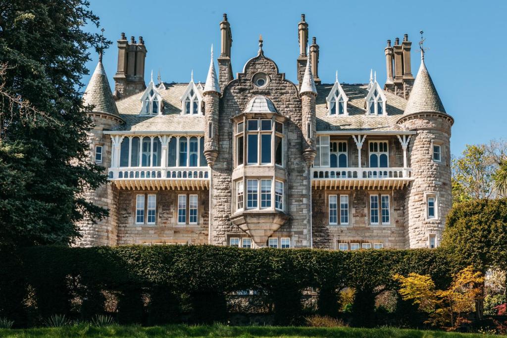 un vieux château avec une haie en face dans l'établissement Château Rhianfa, à Menai Bridge