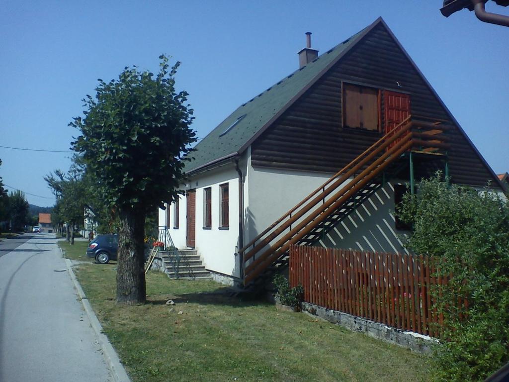 a house with a black roof and a red door at apartman liker in Ravna Gora