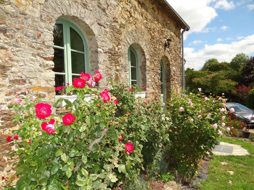 una casa de piedra con rosas frente a una ventana en Logis de la Provosterie en Ahuillé