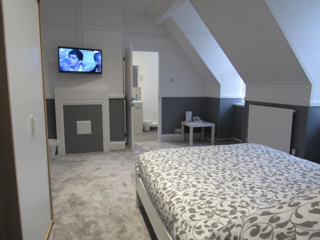 a bedroom with a bed and a tv on the wall at Pear Tree Inn in Welwyn Garden City
