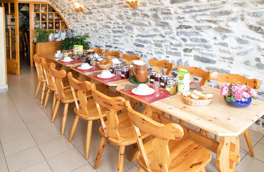 una larga mesa de madera con sillas y comida. en La Roche du Croue en Aussois