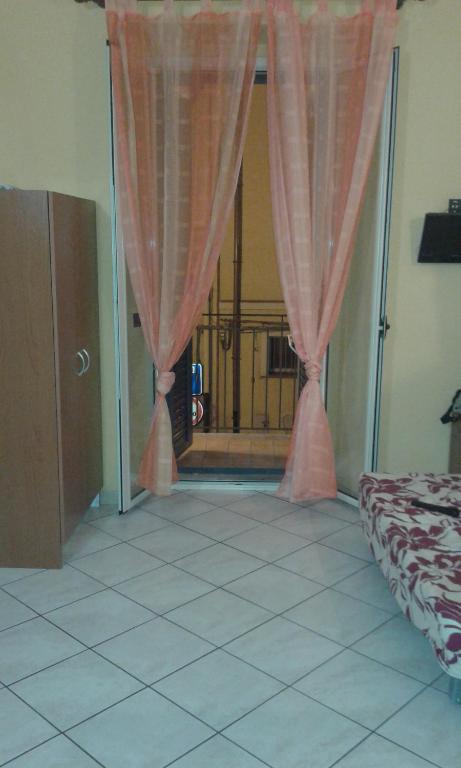 a bedroom with a window with pink curtains and a door at Lina House in Giardini Naxos