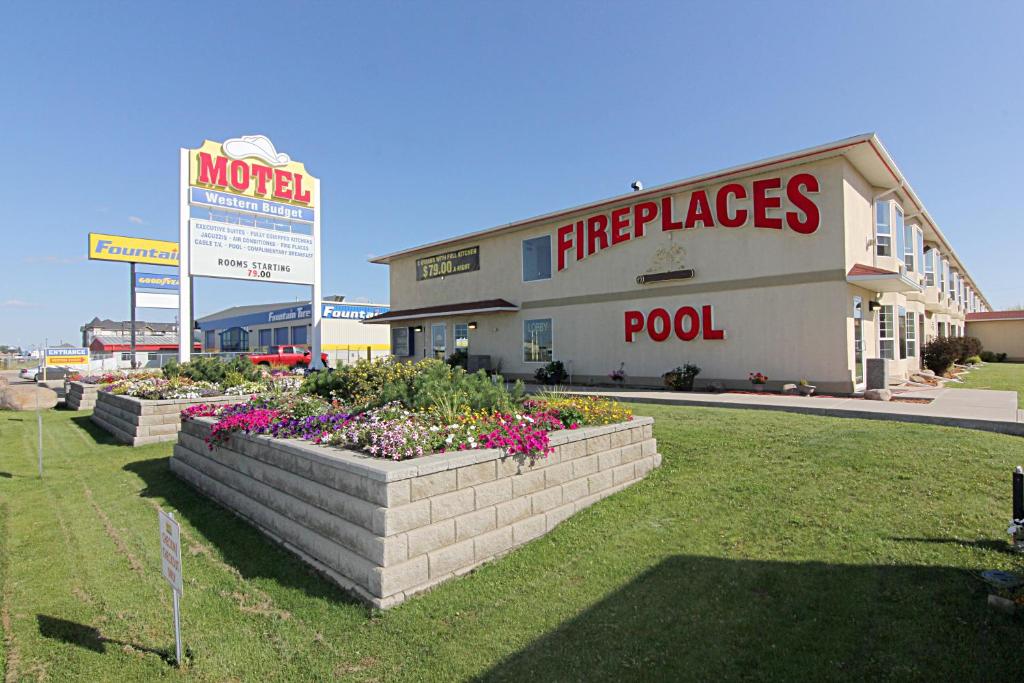 a large building with flowers in front of it at Western Budget Motel Bonnyville in Bonnyville
