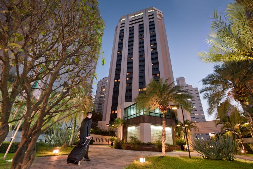 サンパウロにあるNinety Hotelの高い建物の前の公園に立つ男